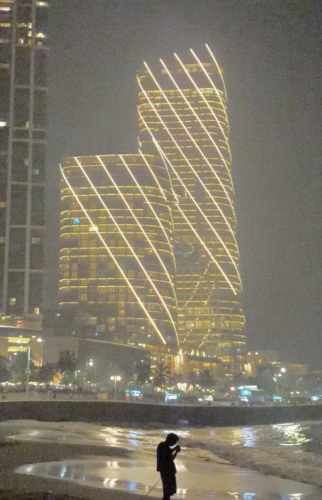 Il s’aide pour cela de la lumière émise par lesgratte-ciels du bord de mer. Nous avons là une photo de style anthropocénique. L’humain semble ridiculement petit par rapport à ses propres artefacts.